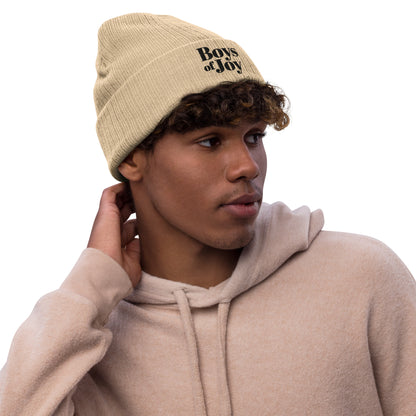 Model in beige hoodie wearing beige ribbed beanie with ‘Boys of Joy’ logo, relaxed three-quarter view.
